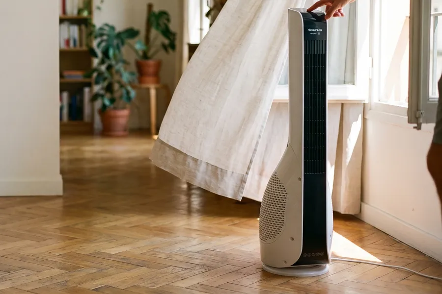 Ventilator turn Taurus Babel Invisible lângă o fereastră deschisă, cu perdeaua de in ridicată de curent